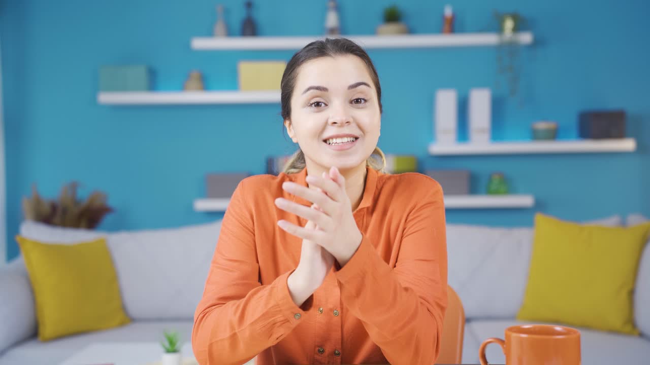 홈 오피스에서 일하는 젊은 기업가 여성이 기쁜 소식을 박수를 치고 축하하고 있습니다.