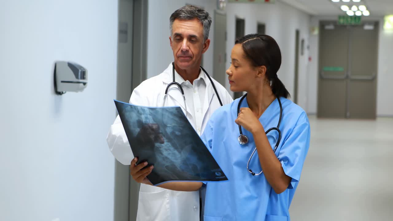 Doctors examining x-ray report in corridor