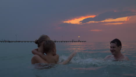 Al-Atardecer,-Madre-Con-Hijo-Nadan-En-El-Mar-De-La-Ciudad-De-Perea,-Grecia