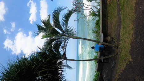 Toma-Vertical-De-Una-Persona-Sentada-Y-Mirando-Las-Olas-Del-Mar-En-La-Playa-De-Balian,-Popular-Lugar-De-Surf-En-Indonesia