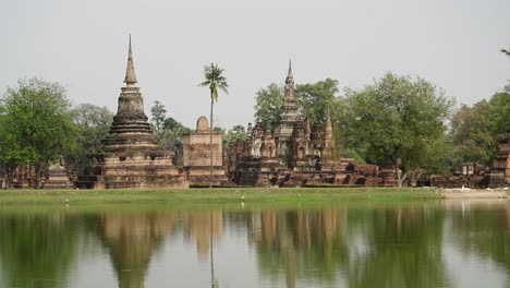 ancient buddhist temples reflected in water at sukhothai historical park, thailand