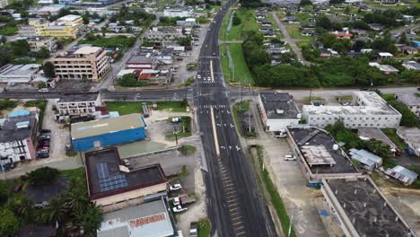 Drone-following-middle-road-with-traffic-through-city,-Saipan,-Northern-Mariana-Islands