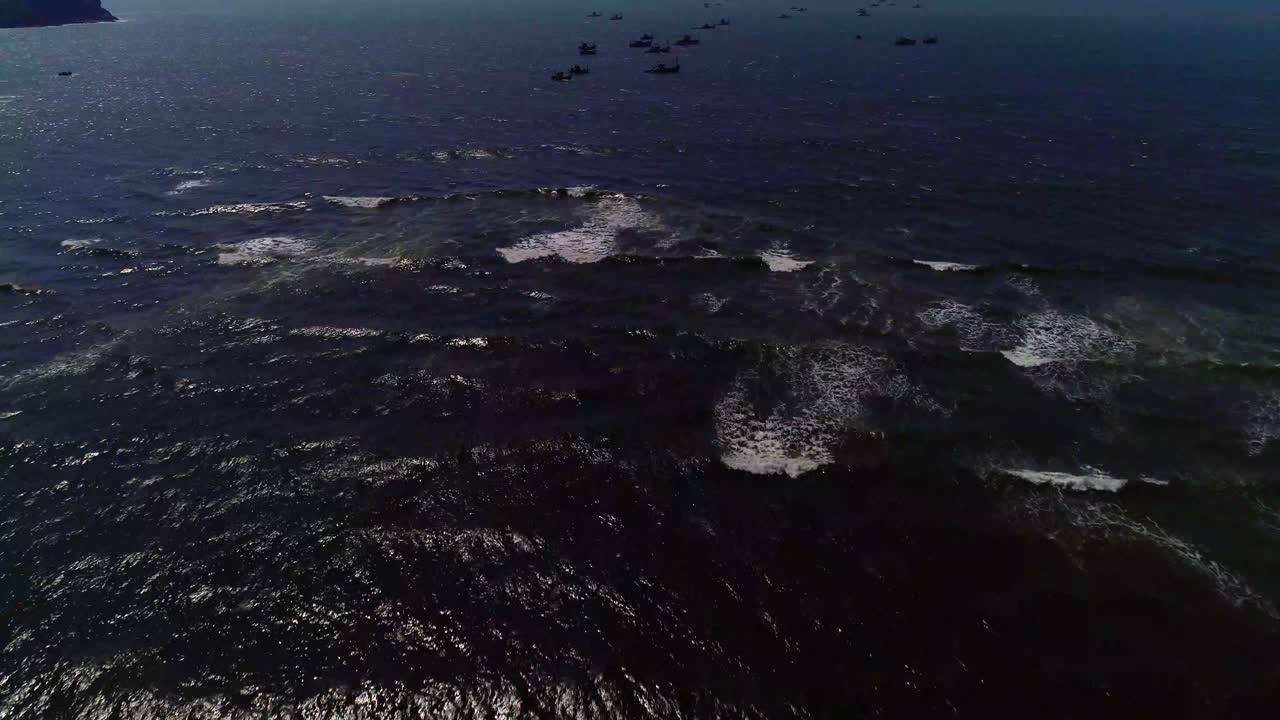 Moving forwards towards fishing boats with waves moving towards shore drone footage