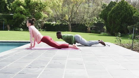 happy diverse couple exercising yoga in sunny garden, slow motion, copy space