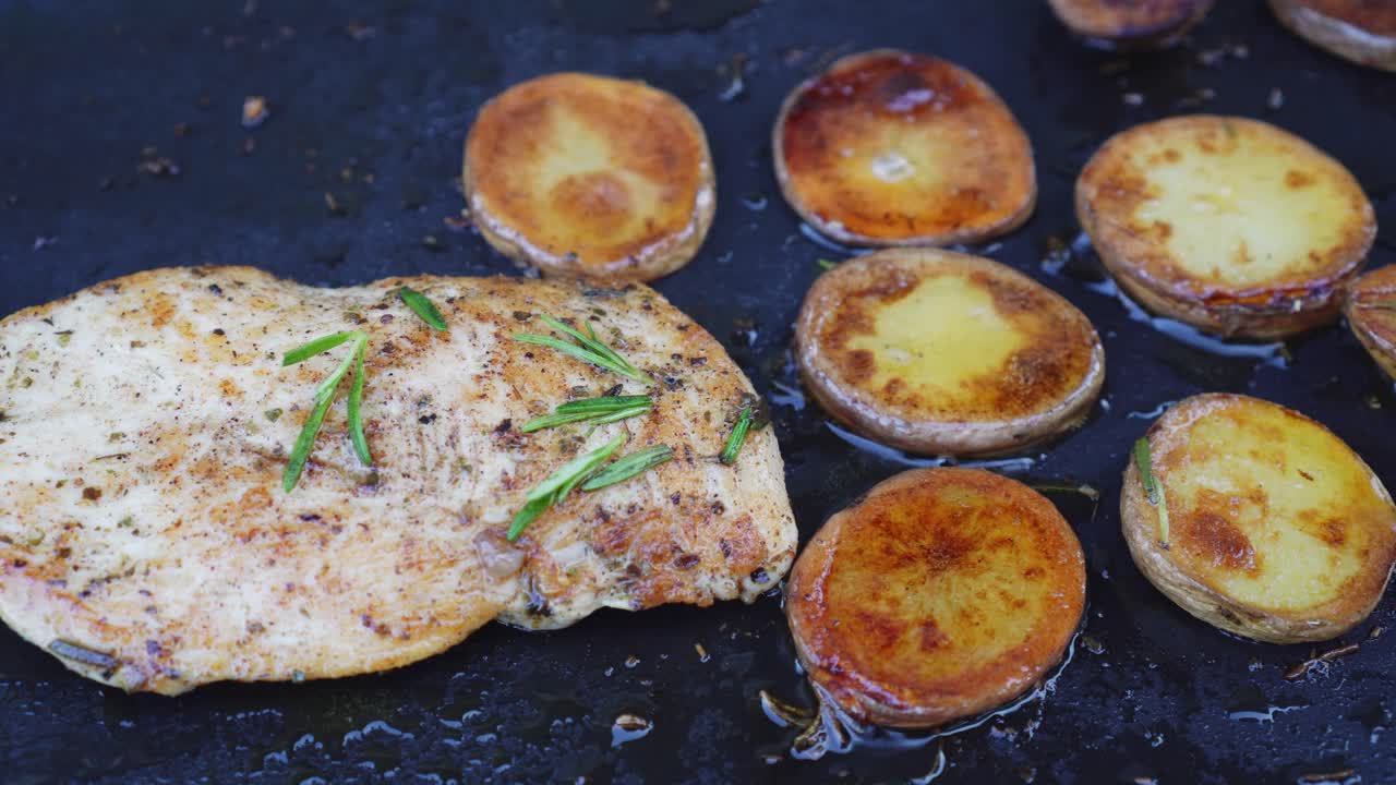 Chicken meat steak and sliced potatoes on grill pan, top down closeup view