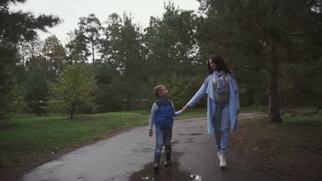 mother and son walking in the park on a rainy autumn day