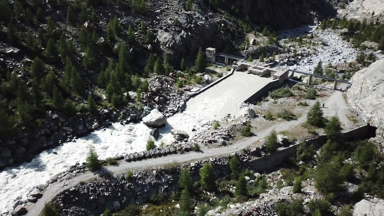 Drone aerial view of a mountain stream near fir forest in a Swiss alps valley