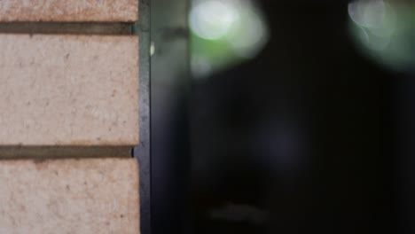 beautifully shot alternate angle close up of a lock on a screen door with hands reaching in to open the screen door and slide open the glass inner door and enter the property, with stylish bokeh