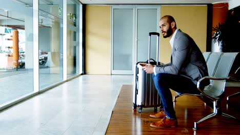 un hombre de negocios enviando mensajes de texto por teléfono móvil en el aeropuerto.
