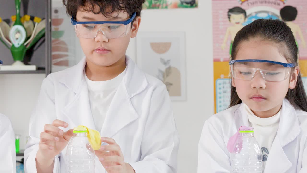 Siswa-siswi muda Thailand berjas lab dan berkacamata pengaman melakukan percobaan reaksi kimia