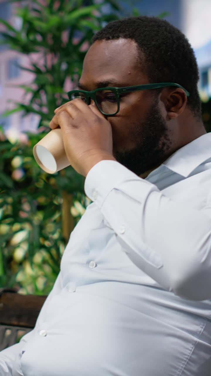 Vertical Video African american male working online from a bench in the park