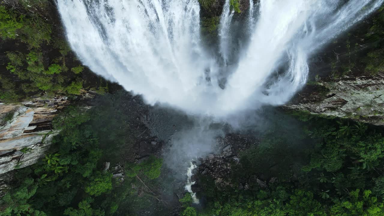 una vista única corriendo por una majestuosa cascada que se derrama en una exuberante piscina de rocas de la selva tropical debajo