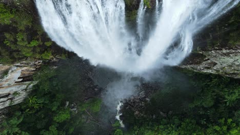 unique view rushing down a majestic waterfall spilling into a lush tropical rainforest rock pool below