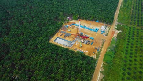 cinematic drone shot of onshore drilling and workover rig structure and rig equipment for oil exploration and exploitation in the middle of jungle surrounded by palm oil trees during sunset time