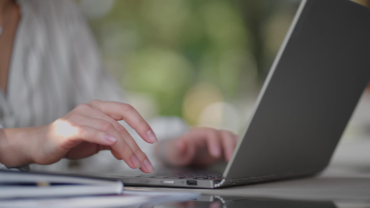 close-up of a woman typing on a laptop keyboard while sitting in a summer cafe. Remote work of a freelancer. Print computer code
