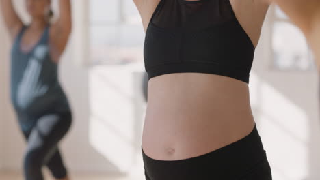 yoga class portrait young pregnant caucasian woman practicing poses holding belly enjoying group exercise in fitness studio