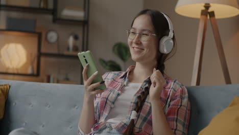 young woman listening to music and dancing on couch
