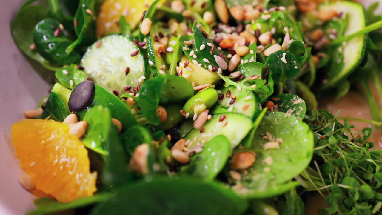Close up of a green salad with seeds and oranges