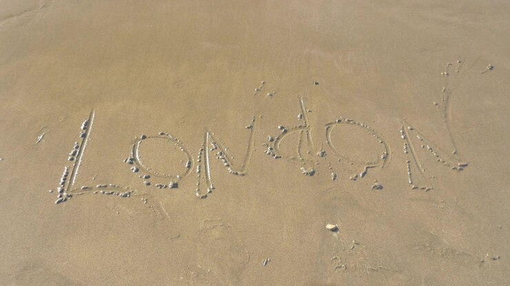 Sea wave washing London written on the sand