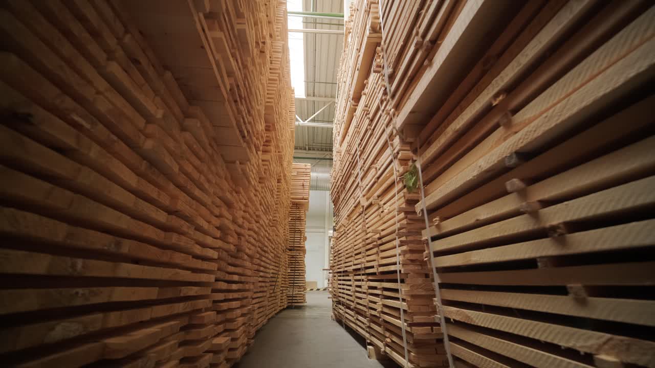 Pasillo largo con pilas de tablones de madera en un almacén de madera