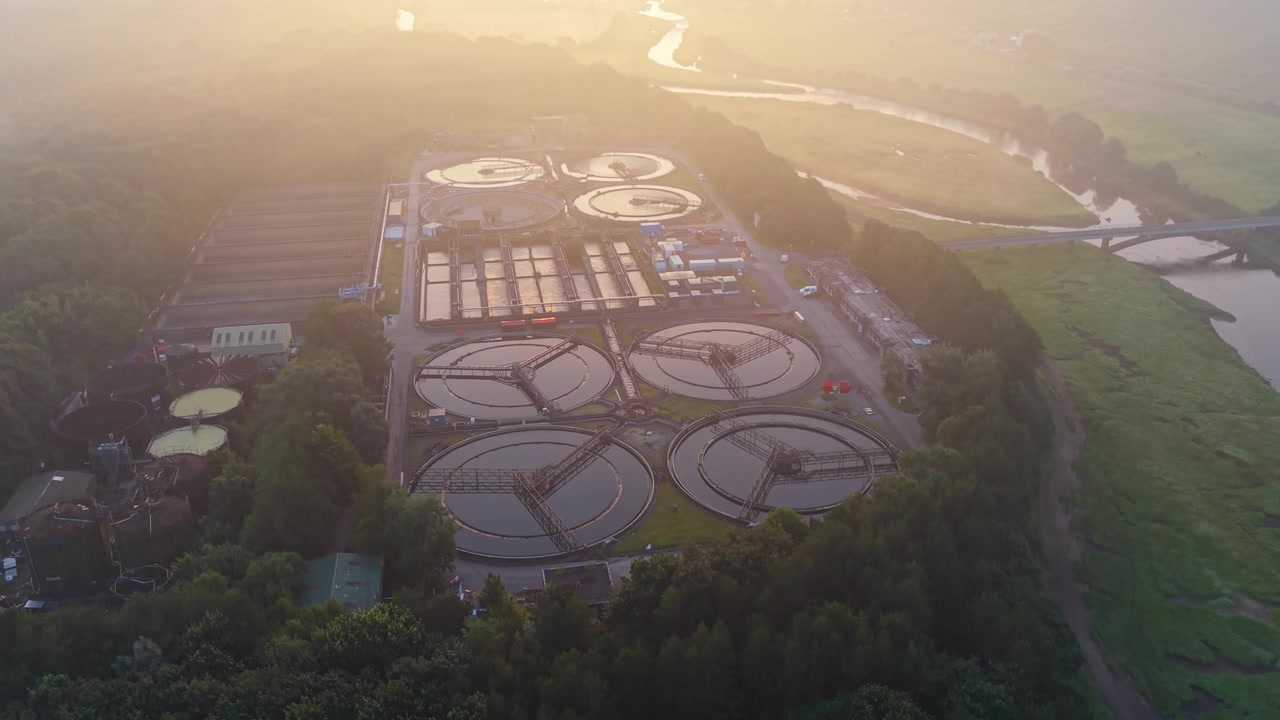 Rising View of Water Treatment Plant and wastewater recycling facility at sunrise with River nearby. Sewage Release to Environment Concept. Clean tech, sustainability, and environmental engineering.