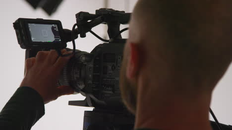 primer plano de un operador de cámara de cine masculino enfocando la cámara usando un monitor filmando o grabando video en el estudio 1