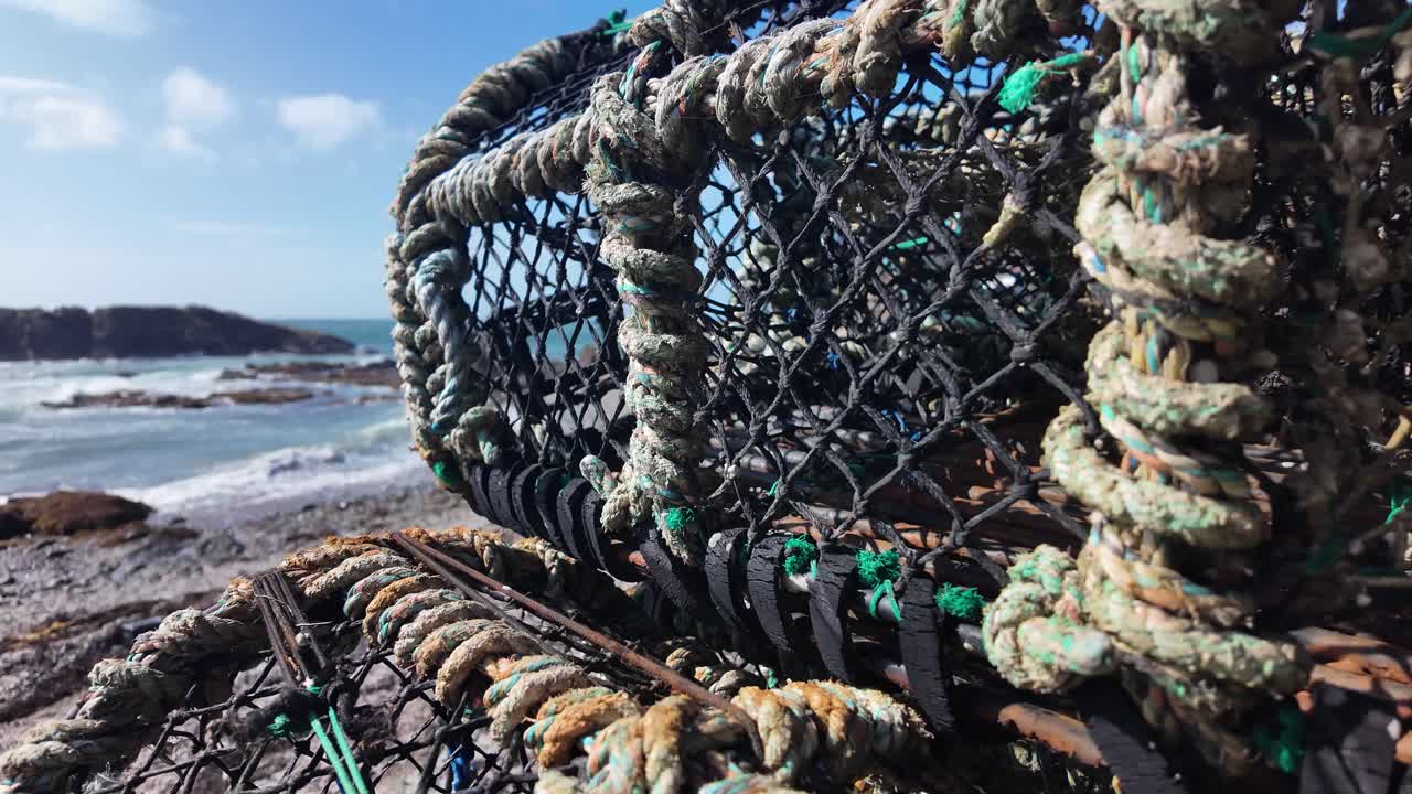 Old crab traps resting on the rugged Isle of Man coastline under a blue sky. close up, push forward