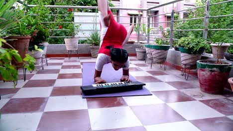 very young indian girl doing handstand yoga with hands and playing music keyboard with both hands has flexible body like rubber