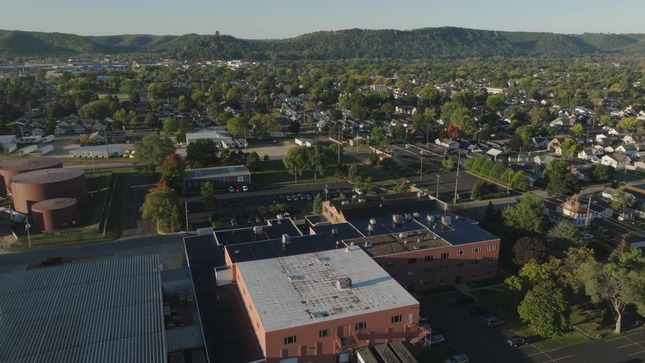 Riprese drone di un edificio commerciale con unità HVAC sul tetto, circondato da un paesaggio di piccola città a Winona, Minnesota, durante il giorno con cielo sereno.