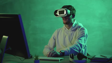 hombre usando un auricular vr y una computadora en un fondo colorido