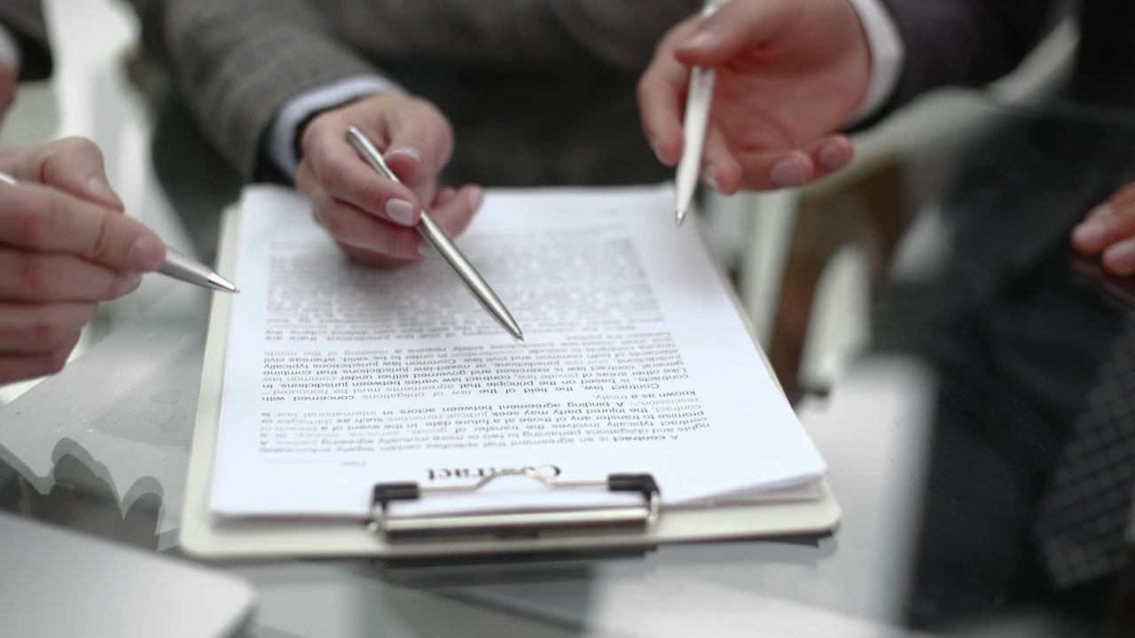 Manos profesionales señalando un documento de contrato durante una reunión de negocios