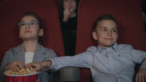 children eating popcorn in the cinema