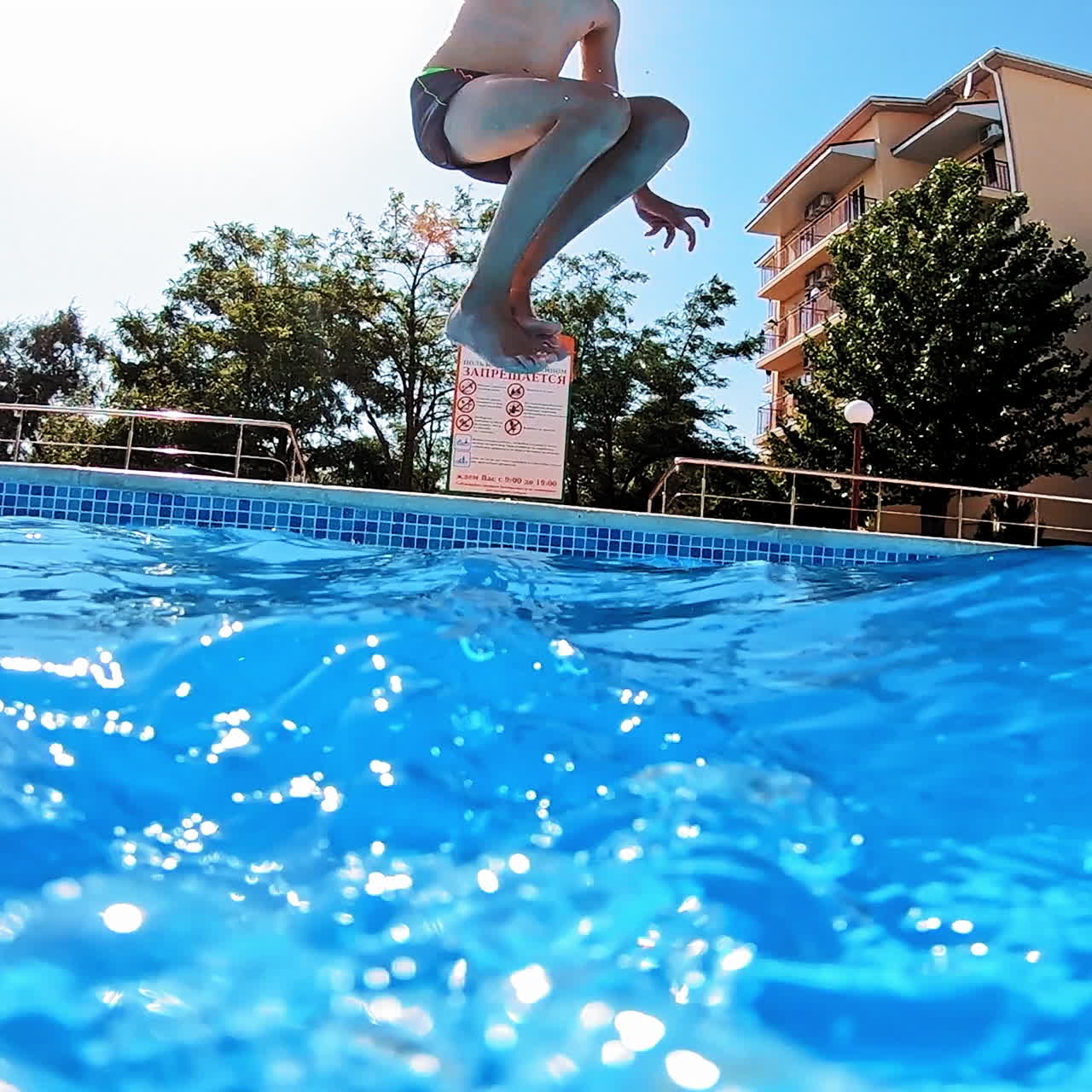 Boy jumping into the clear water in the swimming pool. Young guy jumps underwater on a blue background. Water with bubbles inside the pool.