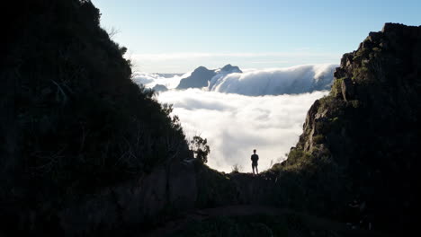 man standing in mountain top, above the clouds, overview at earth