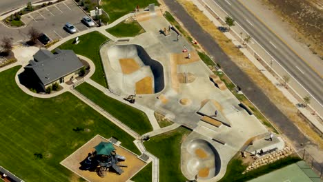 static aerial view of a skate park with kids having fun in summer - slow motion