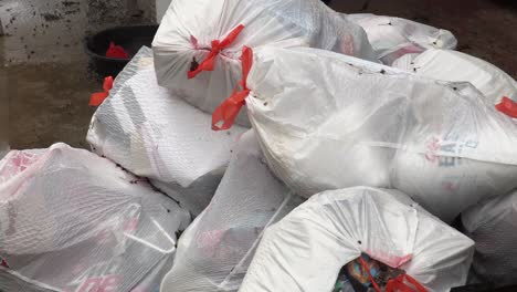 drawstring kitchen trash bag being tossed onto a pile of garbage