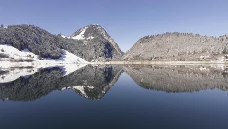 Movind-drone-shot-over-a-mirroring-lake-in-the-swiss-mountains