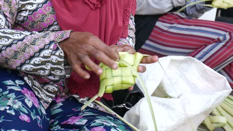 primer plano de una mujer haciendo ketupat a mano, plato especial servido en la celebración del ied fitr en indonesia