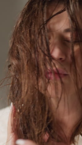 una mujer bonita hidrata el cabello mojado con una emulsión eficaz en la ducha a cámara lenta. sprays de aerosol muy eficaces para suavizar el cabello en la ducha