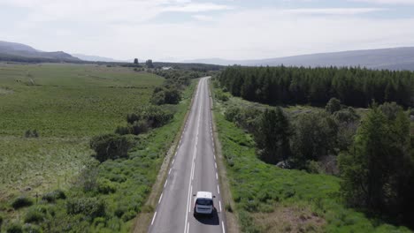 car driving on rural road in iceland with green landscape, aerial