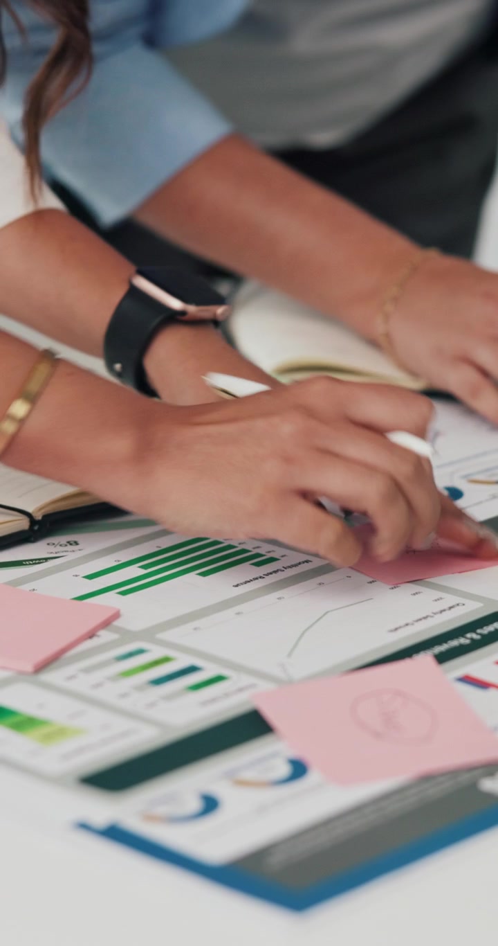 Business Professionals Analyzing Financial Charts and Writing on Sticky Notes