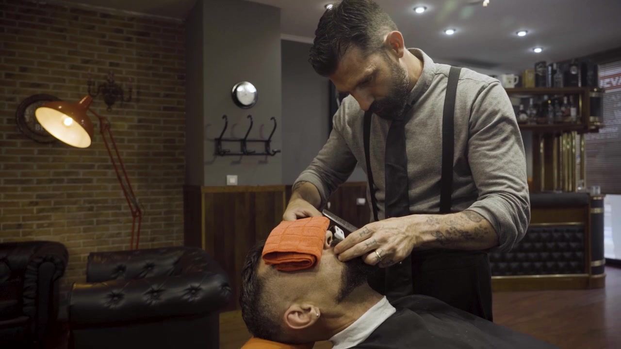 Barbeiro Corta o Bigode de um Cliente com Aparador na Barbearia - close-up
