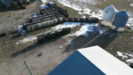 Aerial-Drone-Shot-with-Hay-Bales-of-Two-Women-Setting-up-a-Large-Green-Cattle-Chute-on-a-Farm