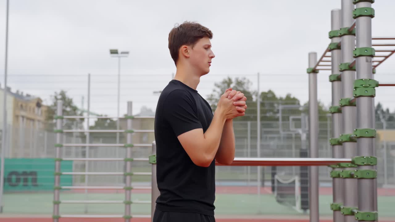 Man twists wrists while stretching arms in warm up before starting training outdoors
