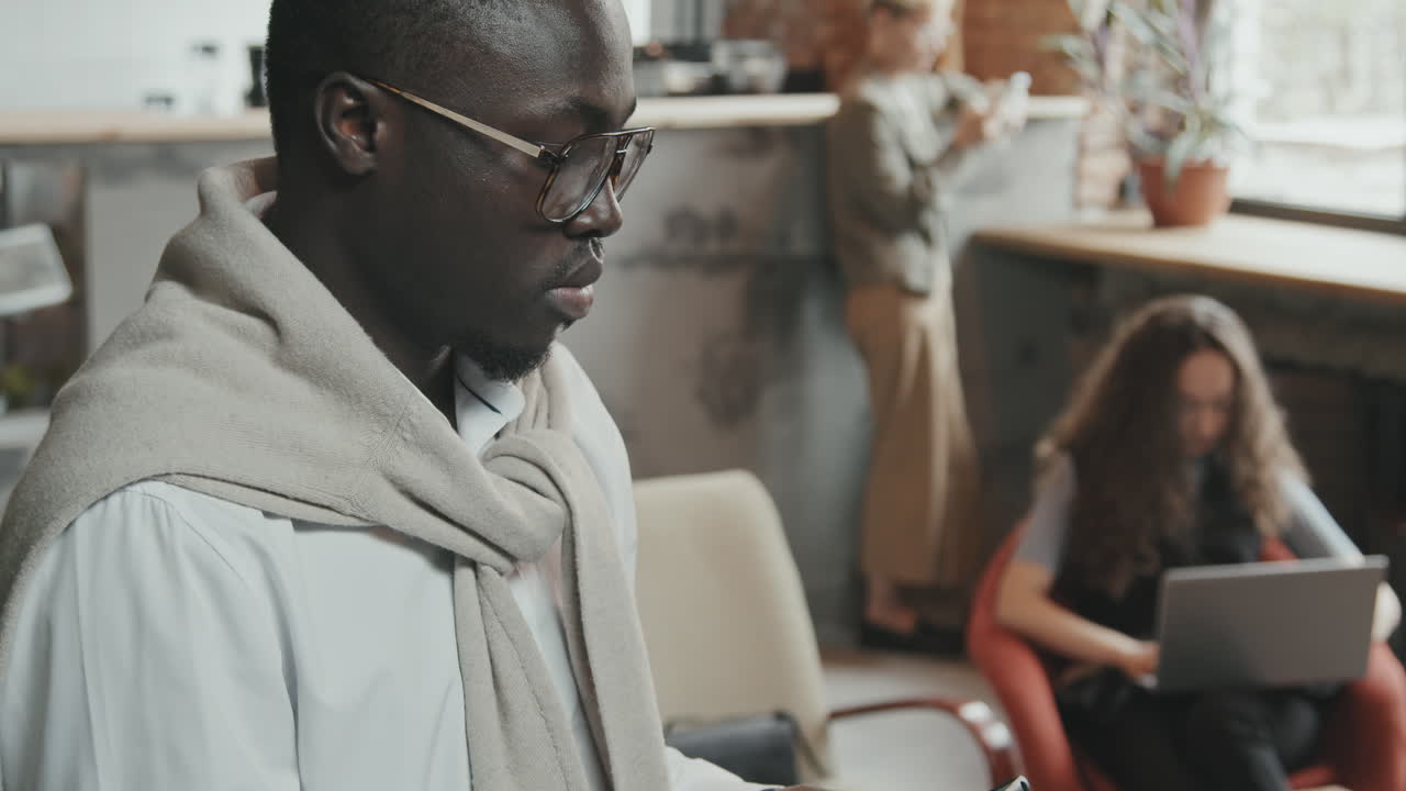 Uomo afroamericano che usa uno smartphone in un ufficio di coworking