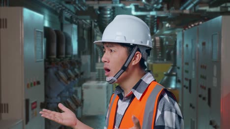 close up side view of ondering asian male engineer with safety helmet saying why working doubtfully in engine control room, work of electrical generators