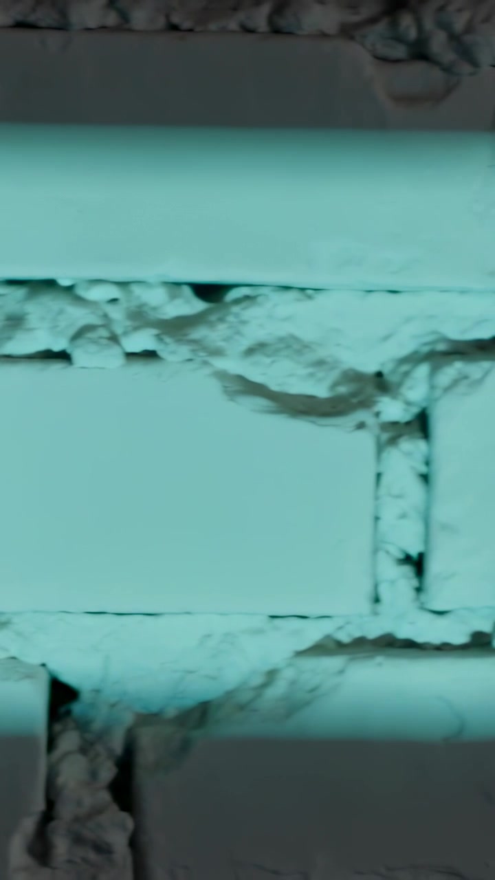 Video verticale: Telecamera che panoramica rivelando un muro di mattoni all'esterno, mostrando una fascia che attraversa la vernice scrostata.