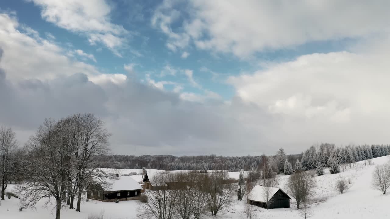 Calm lifestyle living in historic wooden home in countryside. Aerial view of a guesthouse during winter with lots of snow and frost on the trees. Winter wonderland in a sunny day.
