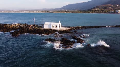 romantic chapel in middle of sea in crete, aerial fly over view