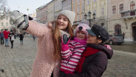 mujeres turistas tomando fotos de selfie en el teléfono móvil con la adopción de una niña en la calle de la ciudad de invierno